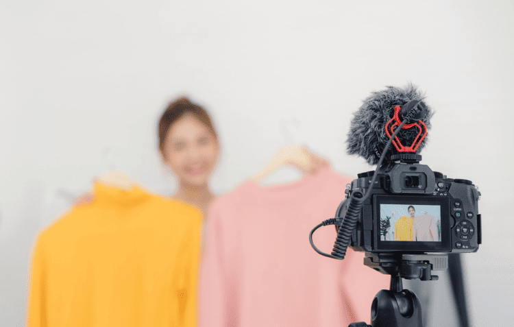 A camera set up in front of mannequins with shirts, promoting influencer marketing tips.