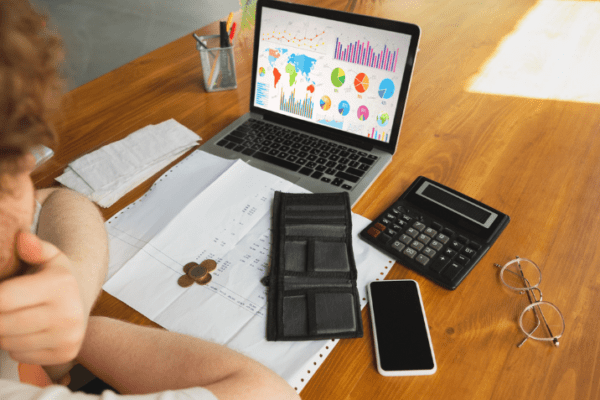 Project Cost Management Software displayed on an open laptop with financial graphs