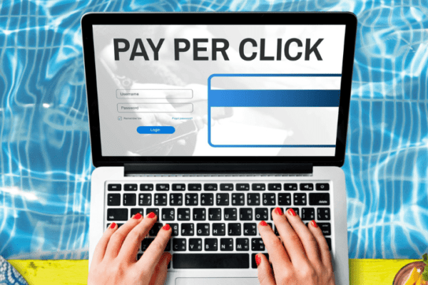 A laptop showing a “PAY PER CLICK” webpage with a login form, promoting PPC advertising guide.