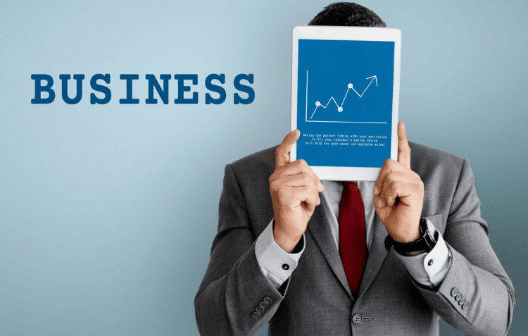 Person holding a blue book titled “BUSINESS” with a white upward trending graph showing to business scaling tips