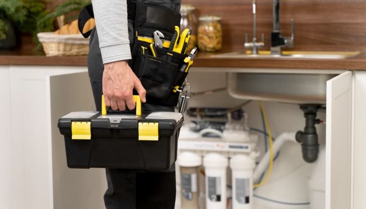 Plumber with tools under sink using AI automation for plumbers.